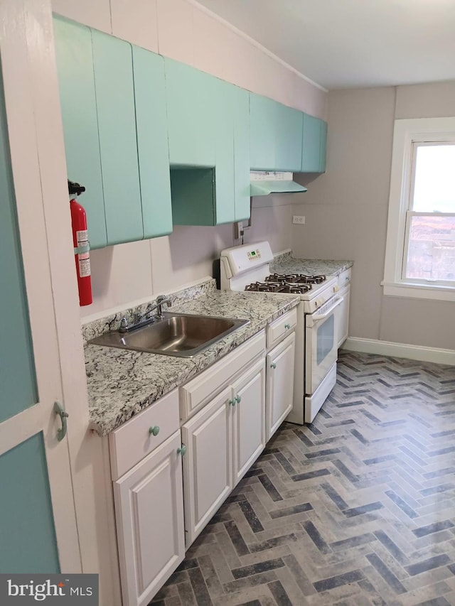 kitchen with sink, white range with gas stovetop, and white cabinets