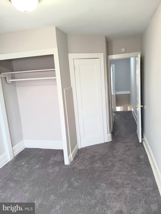 unfurnished bedroom featuring a closet and dark carpet