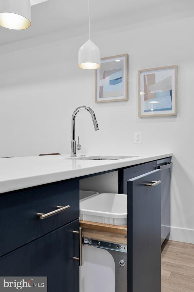 kitchen with pendant lighting, sink, and light hardwood / wood-style flooring