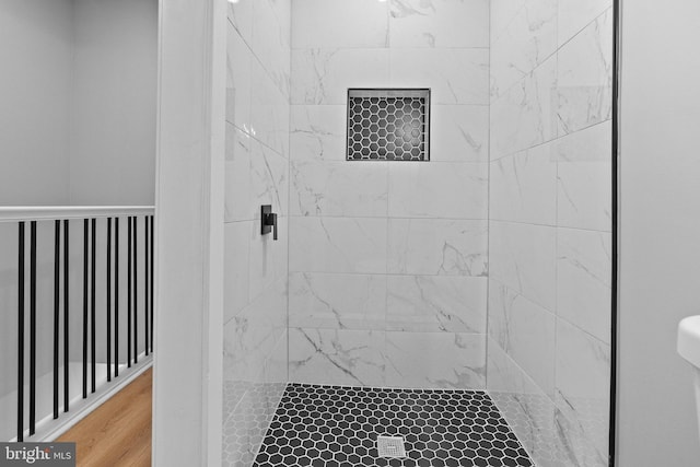 bathroom featuring toilet, wood-type flooring, and tiled shower