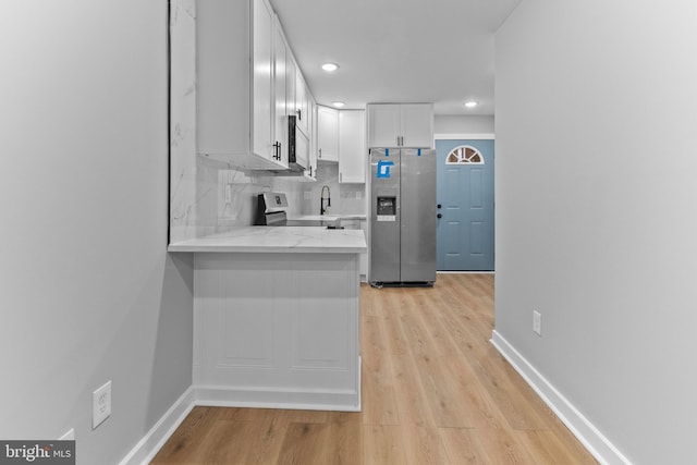 kitchen featuring light hardwood / wood-style flooring, light stone countertops, tasteful backsplash, white cabinetry, and stainless steel appliances