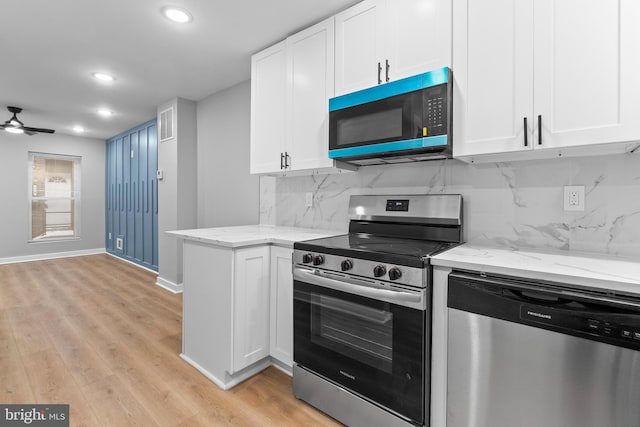 kitchen featuring white cabinets, light wood-type flooring, stainless steel appliances, and tasteful backsplash