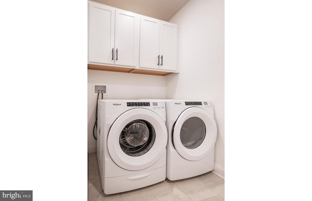 laundry area with washing machine and dryer, light tile patterned flooring, and cabinets