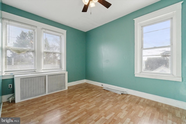 empty room with radiator heating unit, light hardwood / wood-style floors, and ceiling fan