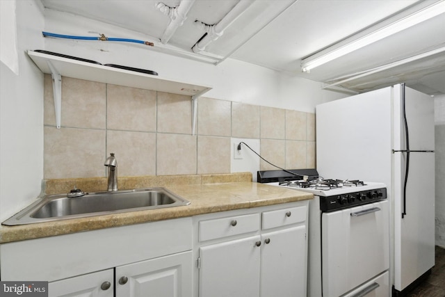 kitchen with tasteful backsplash, white gas stove, white cabinets, and sink