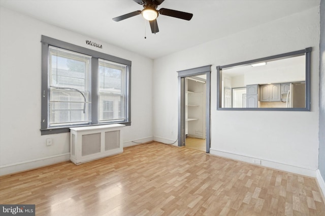 interior space with a spacious closet, light hardwood / wood-style flooring, ceiling fan, and stainless steel refrigerator