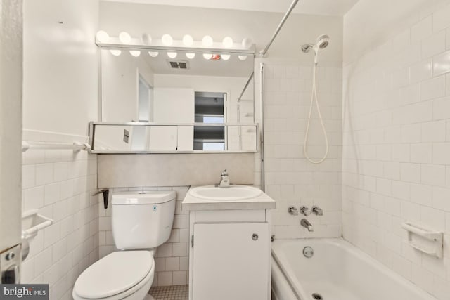 full bathroom featuring vanity, toilet, tile walls, and tiled shower / bath combo