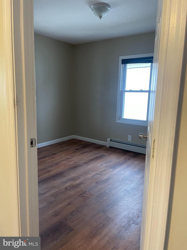 unfurnished room featuring dark hardwood / wood-style floors and baseboard heating