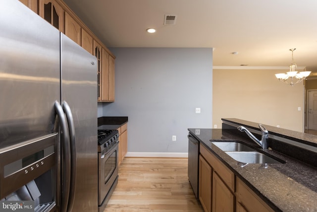 kitchen featuring pendant lighting, sink, dark stone countertops, a notable chandelier, and stainless steel appliances