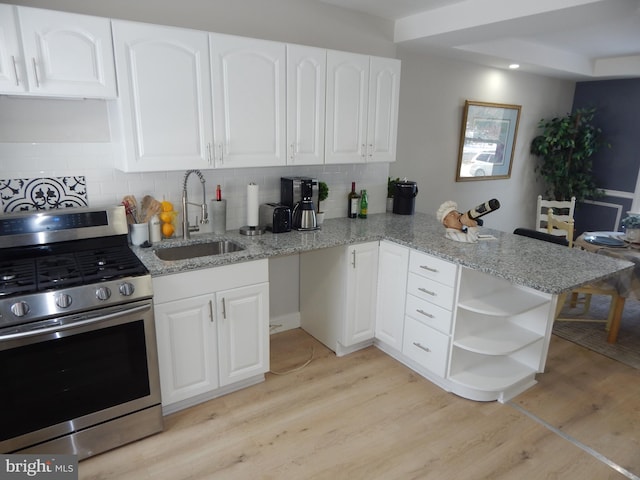 kitchen featuring white cabinetry, sink, light stone countertops, stainless steel range oven, and kitchen peninsula