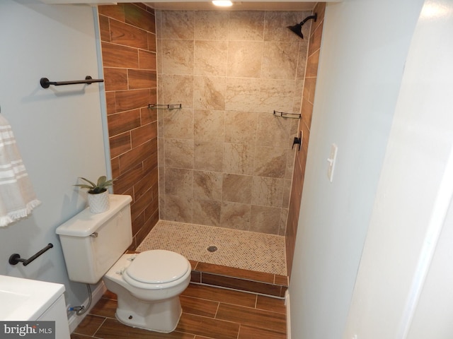 bathroom with a tile shower, vanity, and toilet