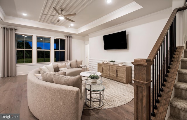 living room with ceiling fan, wood-type flooring, crown molding, and a tray ceiling