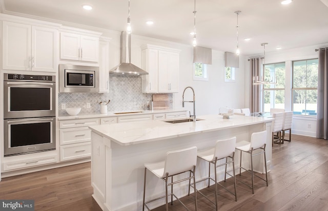 kitchen featuring stainless steel appliances, white cabinetry, a center island with sink, and sink