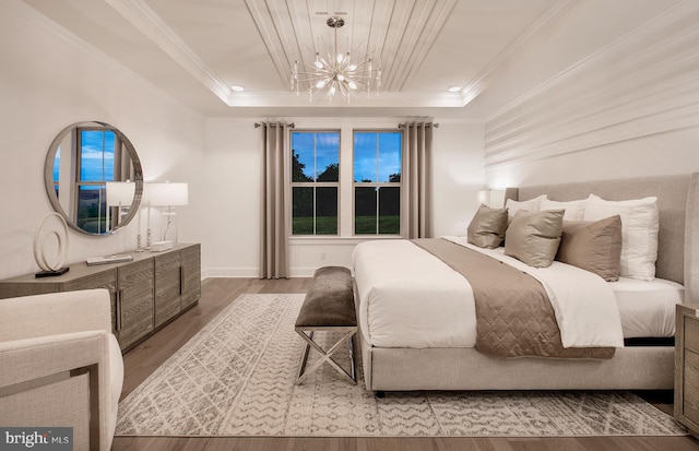 bedroom featuring wood-type flooring, a raised ceiling, a notable chandelier, and crown molding