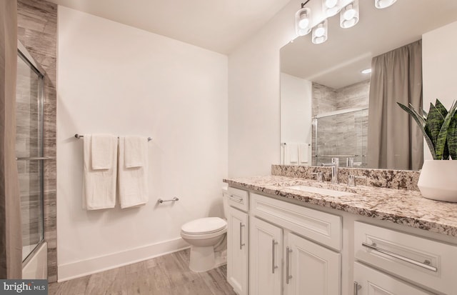 bathroom with wood-type flooring, vanity, toilet, and a shower with door