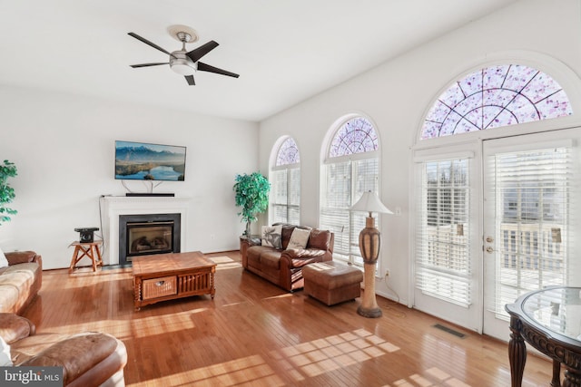 living room featuring light hardwood / wood-style flooring, ceiling fan, and a healthy amount of sunlight