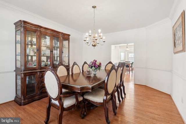 dining area featuring a chandelier, light wood-type flooring, and ornamental molding