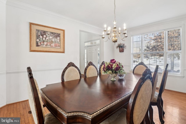 dining room featuring ornamental molding, light wood-type flooring, and a notable chandelier