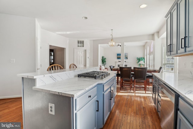 kitchen featuring dark hardwood / wood-style flooring, stainless steel appliances, pendant lighting, a notable chandelier, and a center island