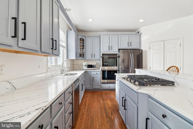 kitchen with dark hardwood / wood-style floors, gray cabinets, light stone countertops, and stainless steel appliances