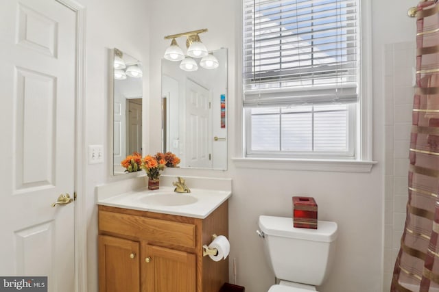 bathroom featuring walk in shower, vanity, and toilet