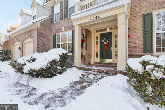 snow covered property entrance featuring a garage