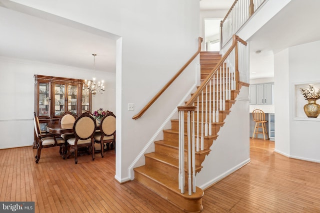 stairs with hardwood / wood-style floors, an inviting chandelier, and crown molding