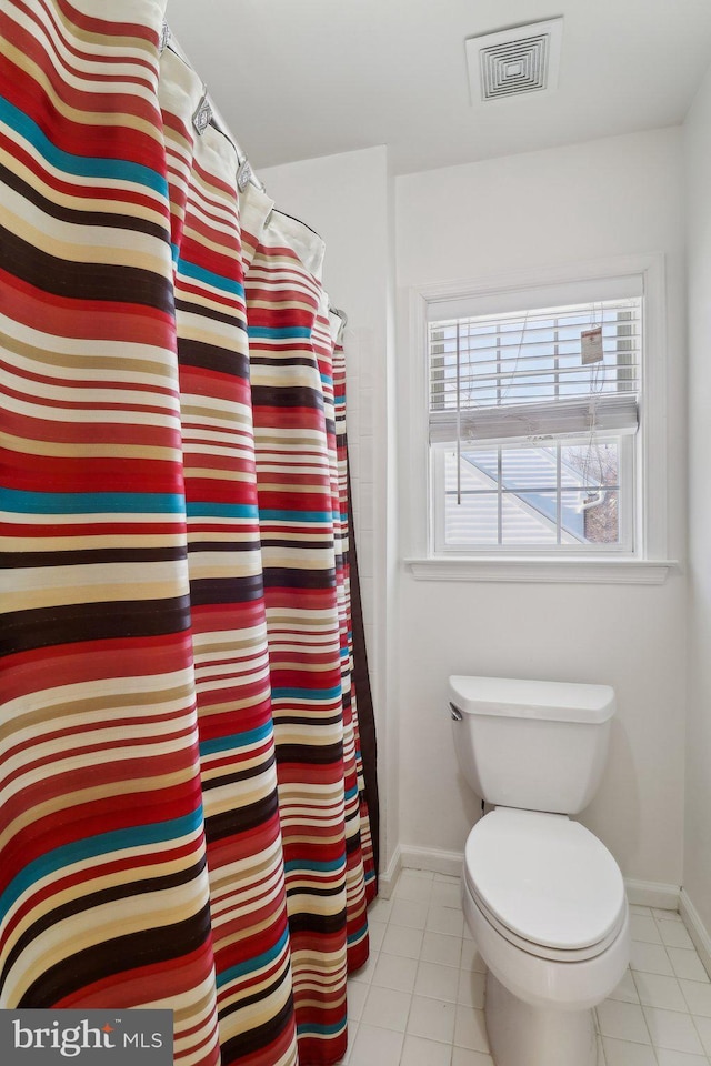 bathroom with tile patterned floors, walk in shower, and toilet