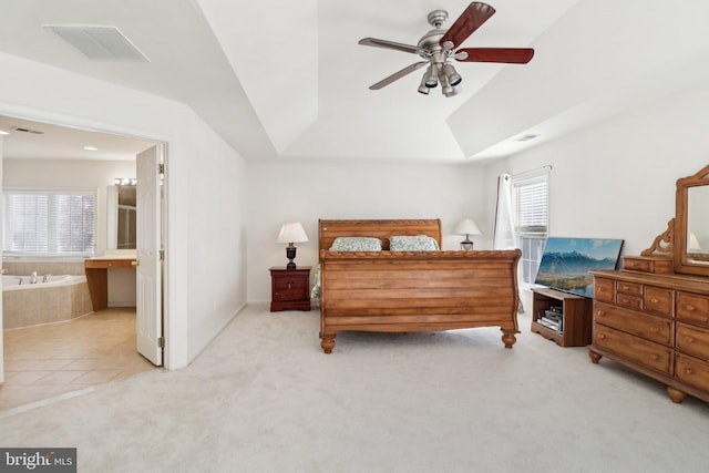 carpeted bedroom featuring a raised ceiling, connected bathroom, and ceiling fan