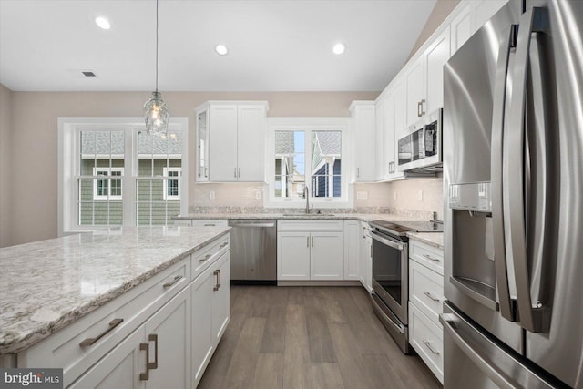 kitchen featuring backsplash, pendant lighting, white cabinetry, and stainless steel appliances