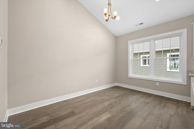 empty room with dark hardwood / wood-style flooring, a chandelier, and vaulted ceiling