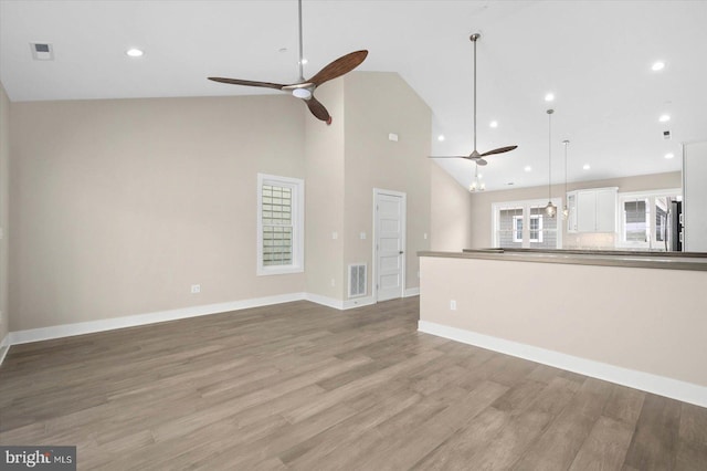 unfurnished living room with ceiling fan, high vaulted ceiling, and light wood-type flooring