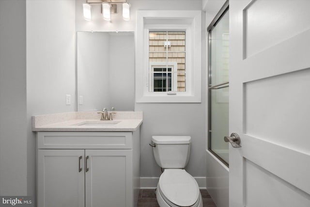 full bathroom with vanity, bath / shower combo with glass door, and toilet