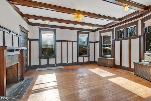 unfurnished living room featuring beamed ceiling, radiator heating unit, and hardwood / wood-style floors