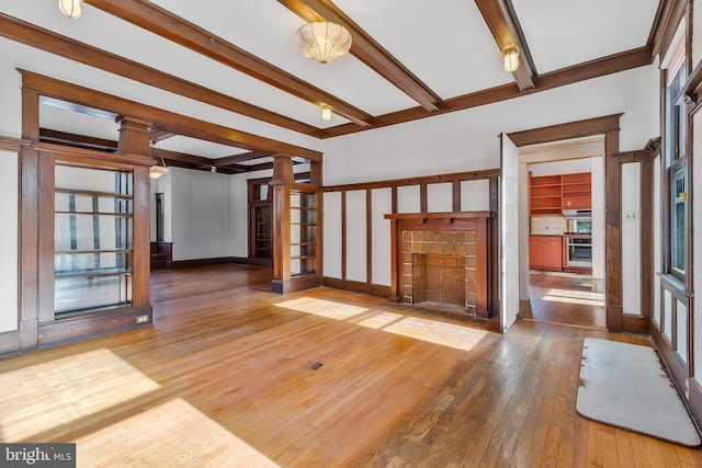 unfurnished living room with ornate columns, hardwood / wood-style floors, and beam ceiling