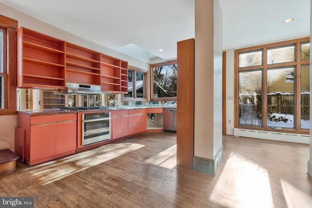 kitchen featuring light hardwood / wood-style flooring, a baseboard radiator, range hood, and appliances with stainless steel finishes