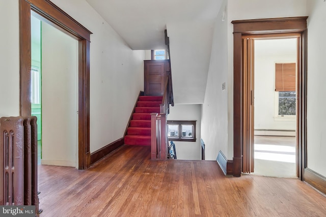 stairway featuring wood-type flooring and baseboard heating