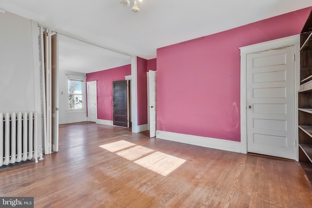 spare room featuring radiator and wood-type flooring