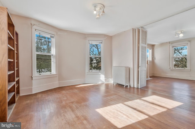 spare room featuring wood-type flooring and radiator heating unit