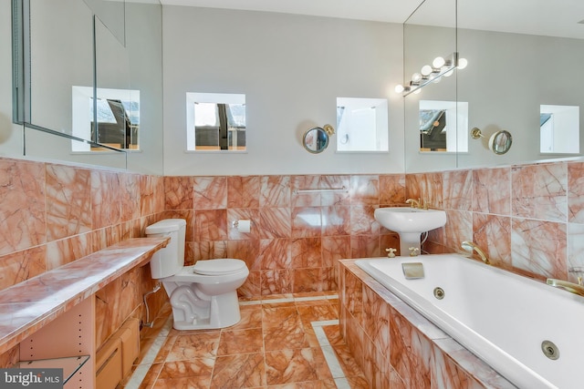 bathroom with a relaxing tiled tub, toilet, sink, and tile walls