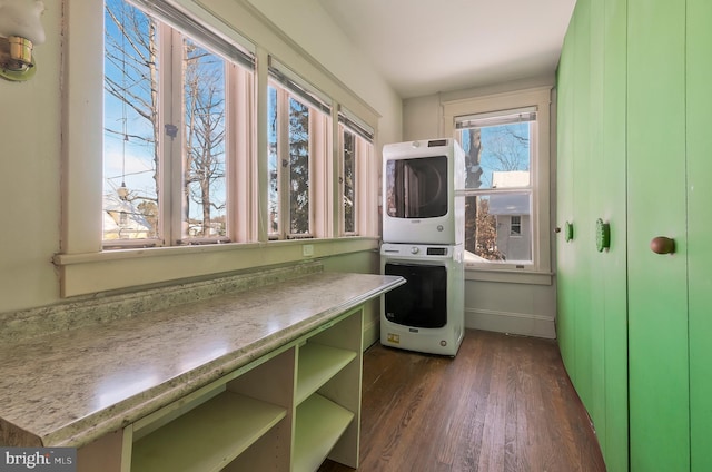 laundry room featuring stacked washer / drying machine, a wealth of natural light, and dark hardwood / wood-style flooring