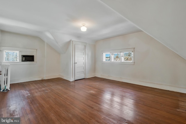 bonus room featuring lofted ceiling, radiator, hardwood / wood-style floors, and a wealth of natural light