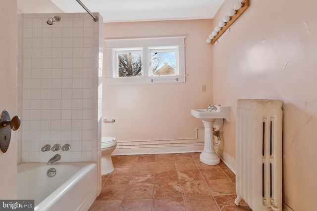 bathroom with tiled shower / bath combo, radiator, and toilet