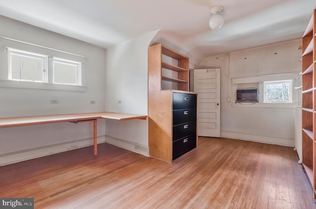 unfurnished office with cooling unit, built in desk, and wood-type flooring