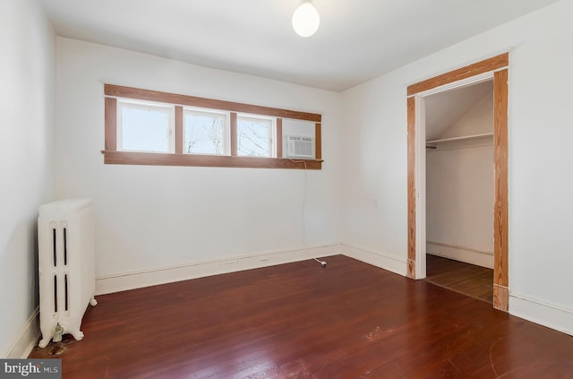 unfurnished bedroom with radiator, cooling unit, dark hardwood / wood-style flooring, and a closet