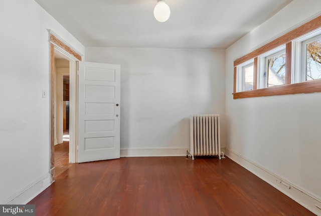 empty room with dark wood-type flooring and radiator heating unit