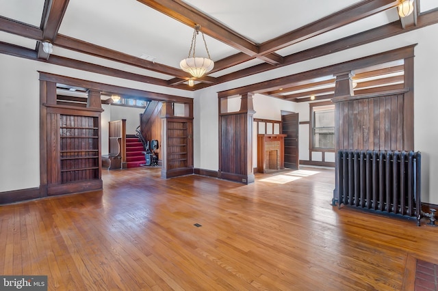 unfurnished living room with beamed ceiling, a healthy amount of sunlight, radiator heating unit, and coffered ceiling