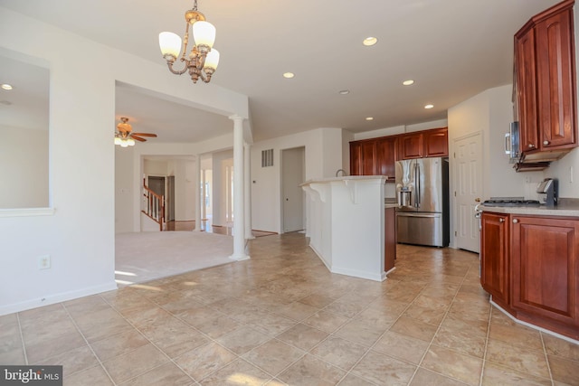 kitchen with ceiling fan with notable chandelier, hanging light fixtures, stainless steel fridge, a kitchen island, and a breakfast bar