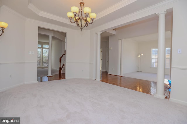 spare room with an inviting chandelier, a raised ceiling, ornamental molding, and carpet flooring