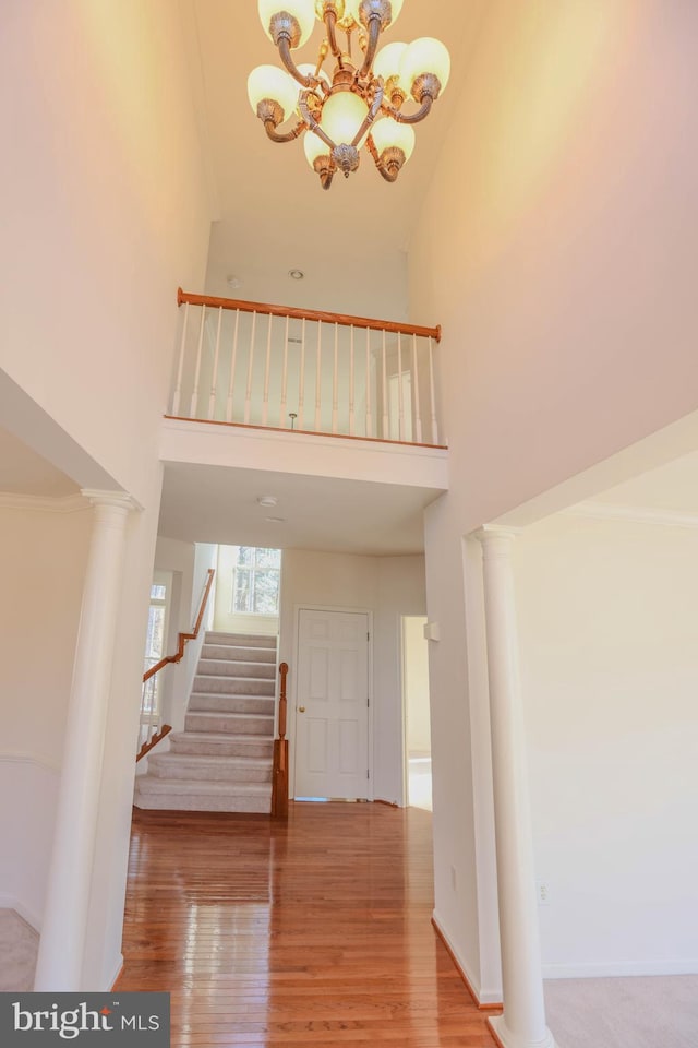 staircase featuring a high ceiling, an inviting chandelier, and hardwood / wood-style flooring